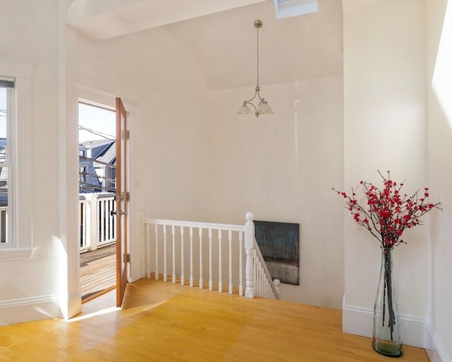 interior space with baseboards, wood finished floors, and an upstairs landing