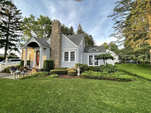 back of house with a yard, a garage, and a chimney