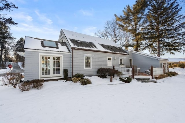 snow covered back of property with french doors