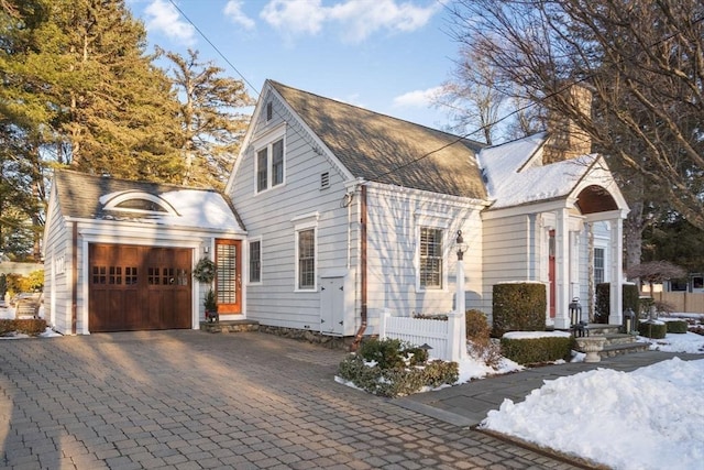 view of property exterior with an attached garage and decorative driveway