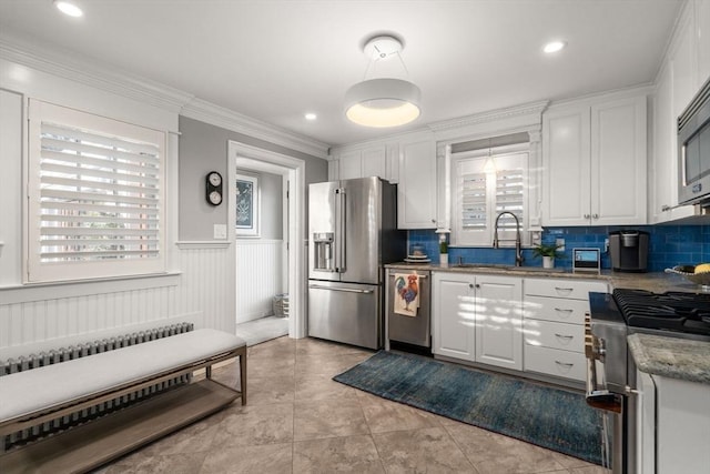 kitchen with high end appliances, radiator heating unit, a sink, white cabinetry, and tasteful backsplash