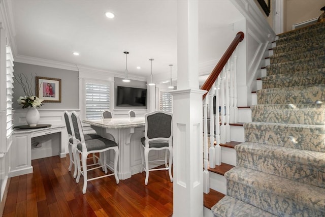 dining space featuring a wainscoted wall, stairs, crown molding, and dark wood-type flooring