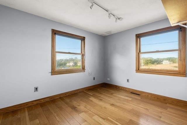 63 Seaside Rd, Scituate, MA 02066 - unfurnished room with rail lighting, healthy amount of natural light, light wood finished floors, and baseboards