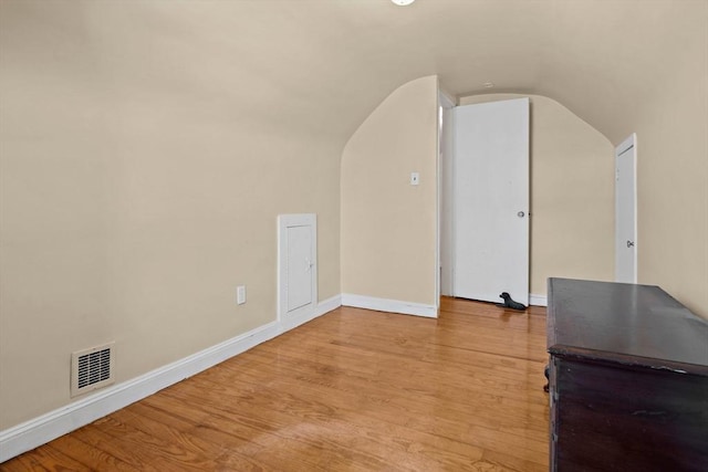 additional living space featuring light wood-type flooring, baseboards, lofted ceiling, and visible vents