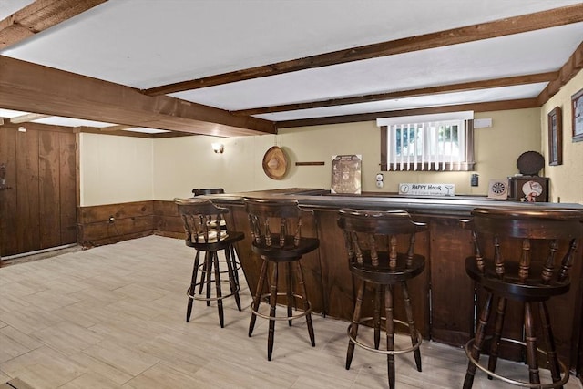 bar with beam ceiling, a bar, and wood walls