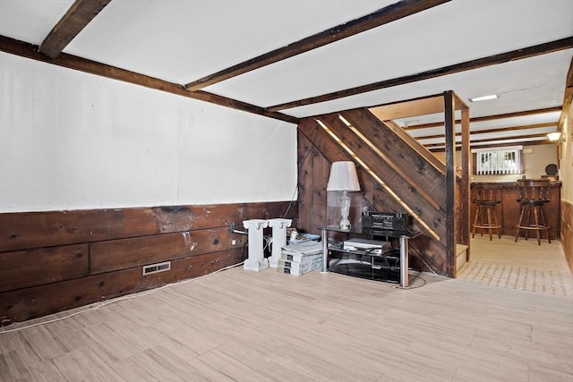 living area with lofted ceiling with beams, visible vents, a bar, and wood walls