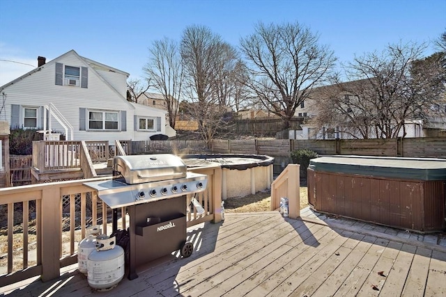 wooden terrace featuring a grill, a fenced backyard, and a hot tub