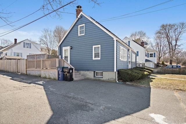 rear view of property with a wooden deck, a chimney, and fence