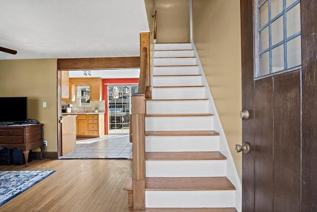 staircase featuring baseboards, wood-type flooring, and a ceiling fan