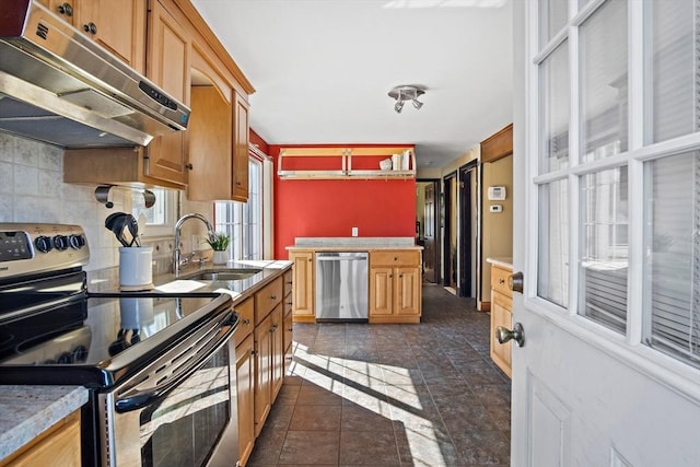 kitchen featuring under cabinet range hood, light countertops, decorative backsplash, appliances with stainless steel finishes, and a sink