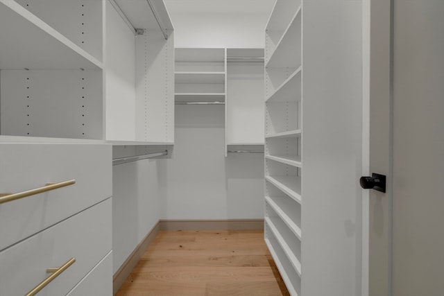 walk in closet with light hardwood / wood-style floors