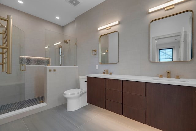 bathroom with tile patterned floors, toilet, a tile shower, and tile walls