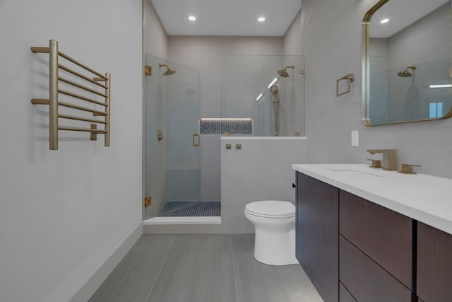 bathroom featuring an enclosed shower, vanity, toilet, and radiator