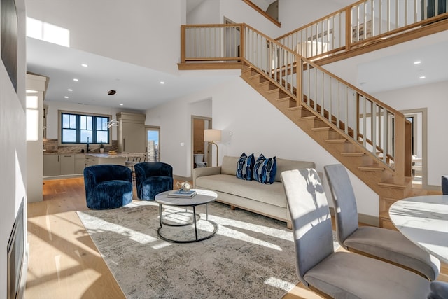 living room with a towering ceiling, light hardwood / wood-style floors, and sink