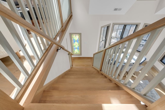 stairway with a towering ceiling and hardwood / wood-style flooring