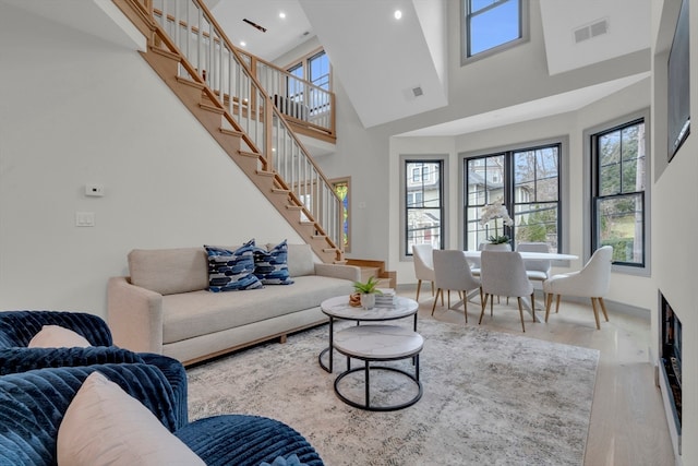 living room featuring a towering ceiling, hardwood / wood-style flooring, and plenty of natural light