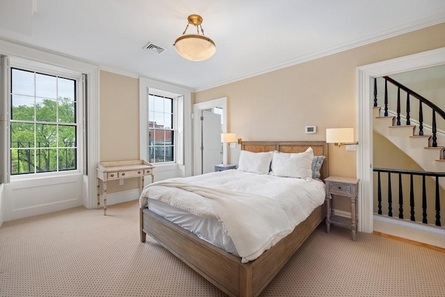 bedroom with ornamental molding, multiple windows, light colored carpet, and visible vents