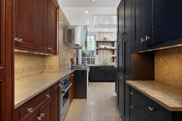 kitchen with stainless steel oven, recessed lighting, open shelves, a raised ceiling, and wall chimney range hood