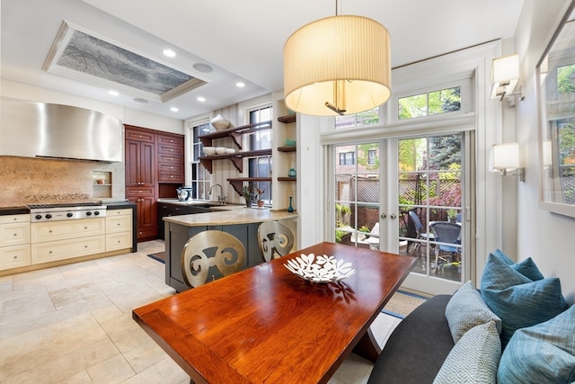 dining space with a wall unit AC, light tile patterned floors, sink, a tray ceiling, and french doors