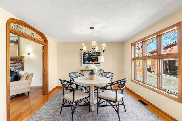 dining area featuring a fireplace, wood-type flooring, and an inviting chandelier