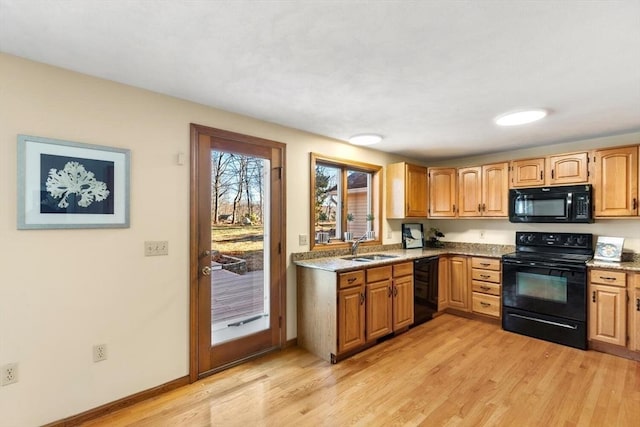 kitchen featuring light stone countertops, sink, black appliances, and light wood-type flooring