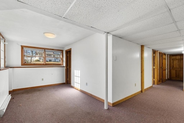 spare room featuring a paneled ceiling, carpet flooring, and a baseboard heating unit