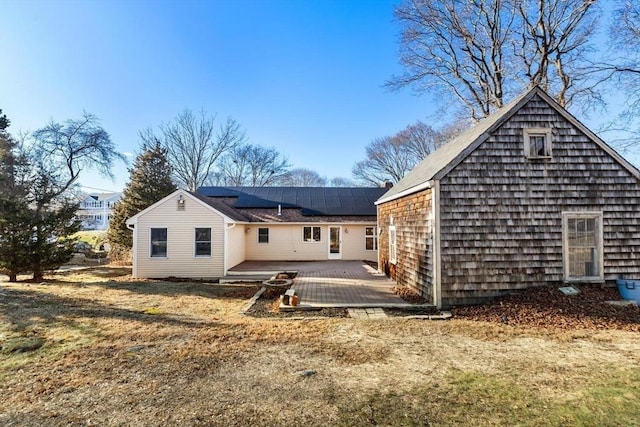 rear view of house featuring a patio area, a yard, and solar panels