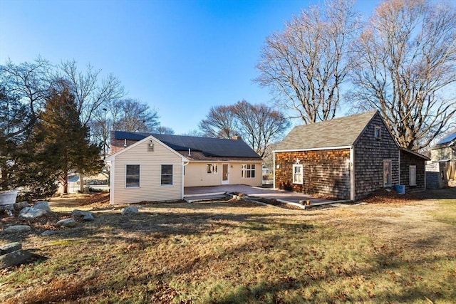 rear view of house featuring a lawn, solar panels, and a patio area