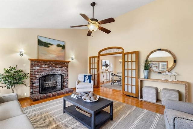 living room featuring french doors, ceiling fan, hardwood / wood-style flooring, a fireplace, and lofted ceiling