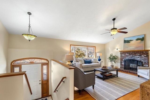 living room featuring hardwood / wood-style flooring, a brick fireplace, ceiling fan, and lofted ceiling