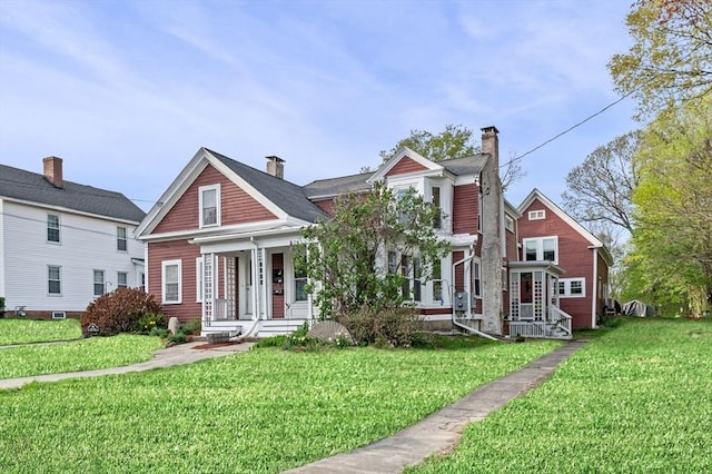 view of front facade featuring a chimney, a porch, and a front yard