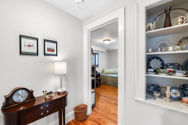 corridor with baseboards and wood finished floors