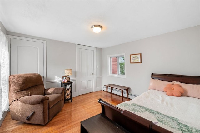 bedroom with a baseboard radiator and light wood finished floors