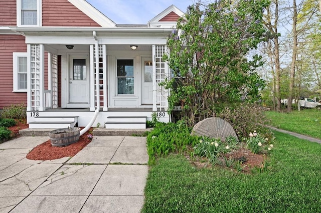 entrance to property with a lawn and a porch