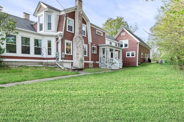 rear view of house with a lawn, a chimney, and entry steps