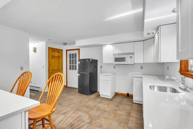 kitchen with a baseboard radiator, sink, white cabinetry, light stone countertops, and black fridge