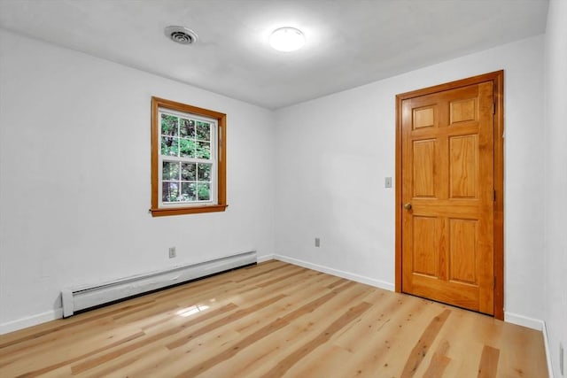 unfurnished room with wood-type flooring and a baseboard heating unit