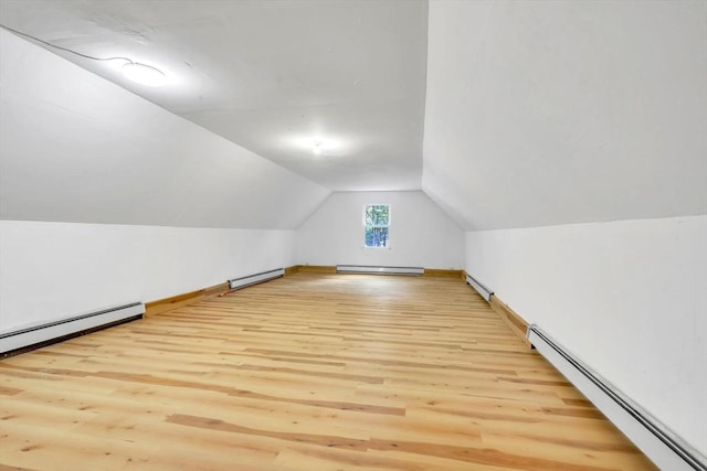 additional living space with a baseboard heating unit and light hardwood / wood-style floors