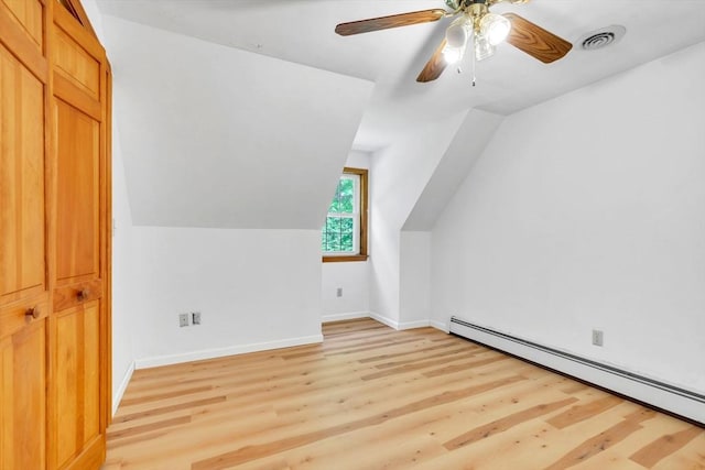 additional living space featuring ceiling fan, light hardwood / wood-style flooring, vaulted ceiling, and a baseboard heating unit