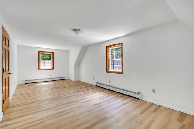 additional living space featuring baseboard heating, light hardwood / wood-style flooring, and lofted ceiling