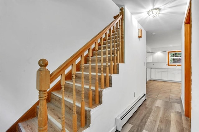 stairway featuring wood-type flooring and a baseboard radiator