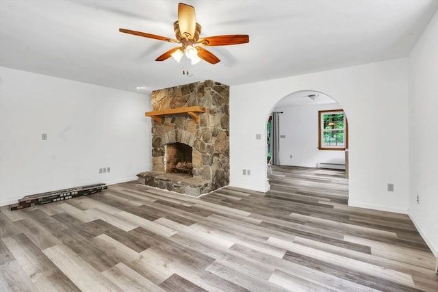 unfurnished living room with light hardwood / wood-style floors, ceiling fan, a baseboard radiator, and a fireplace