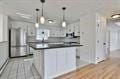 kitchen featuring a peninsula, dark countertops, decorative light fixtures, and wood finished floors