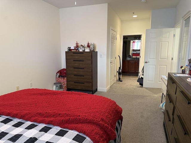 bedroom featuring light carpet, ensuite bath, and baseboards