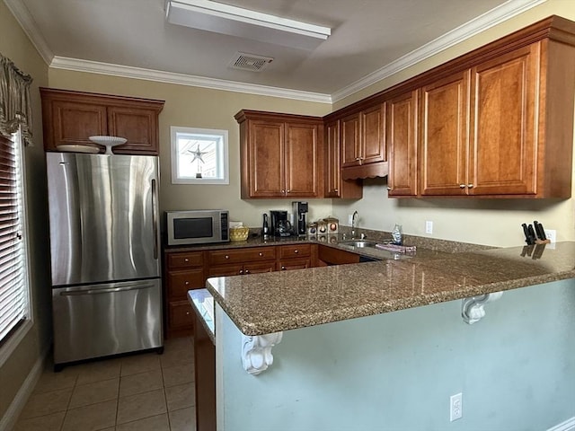 kitchen featuring a breakfast bar area, visible vents, appliances with stainless steel finishes, a peninsula, and tile patterned floors