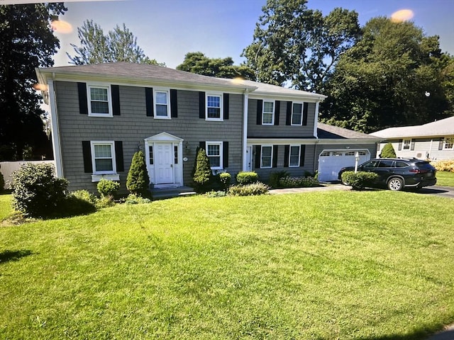 colonial home with an attached garage, driveway, and a front yard