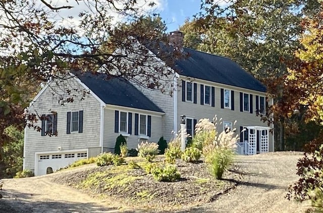 colonial house featuring a garage, driveway, and a chimney