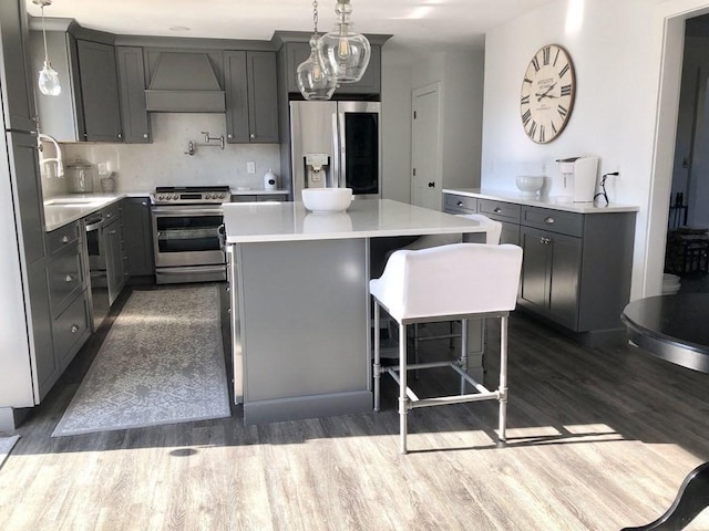 kitchen featuring custom exhaust hood, a sink, dark wood-style flooring, appliances with stainless steel finishes, and gray cabinetry