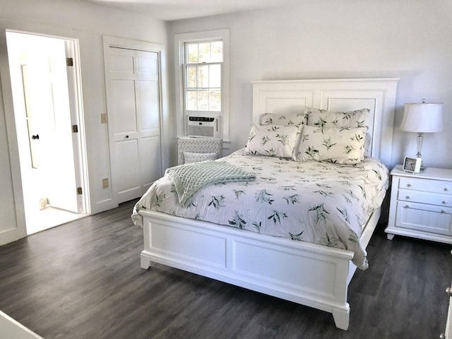 bedroom featuring dark wood-type flooring, cooling unit, and a closet