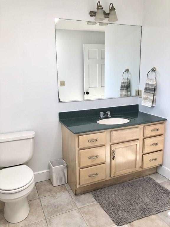 bathroom with toilet, tile patterned floors, vanity, and baseboards